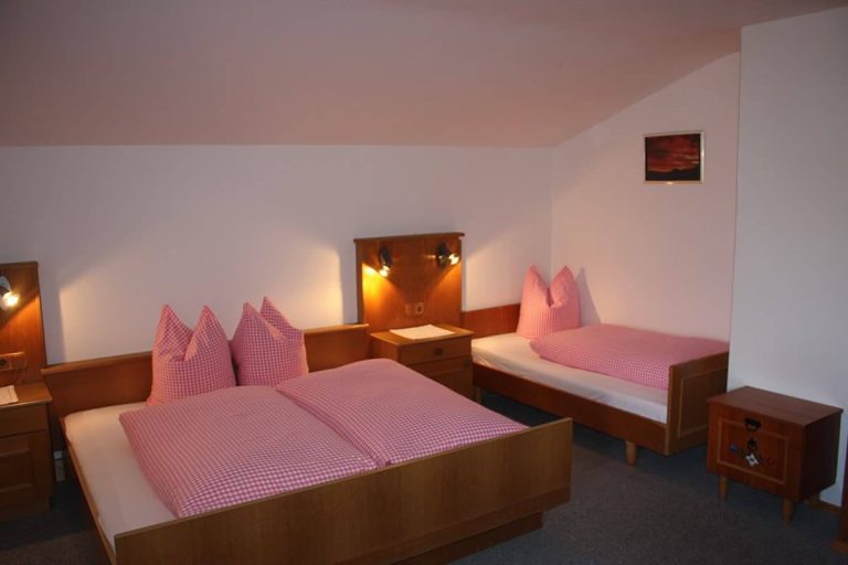 Gemütliches Zimmer mit Doppelbett und Einzelbett, Holzmöbeln, rosa Bettwäsche im Berghotel Großglockner
