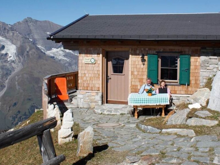 Paar genießt Bergblick an Holztisch vor der Edelweißhütte auf der Edelweißspitze, Großglockner